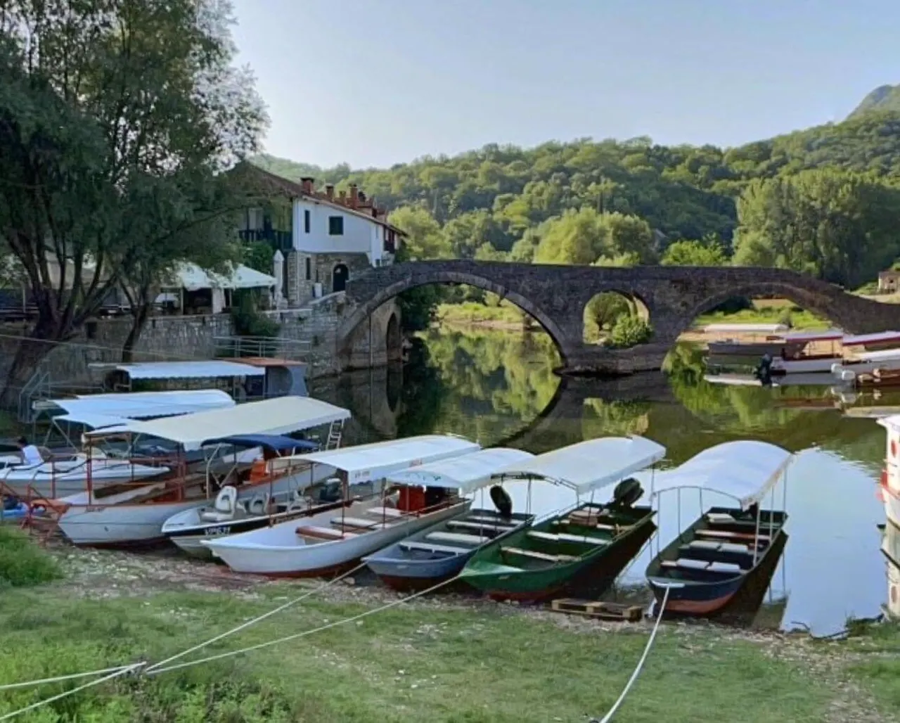 Historic stone bridge over the Crnojevića River with boats moored below