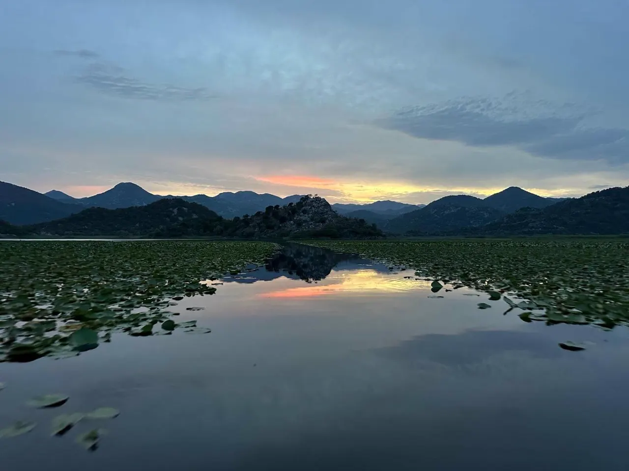 Mountains reflected in still water at sunset on Lake Skadar